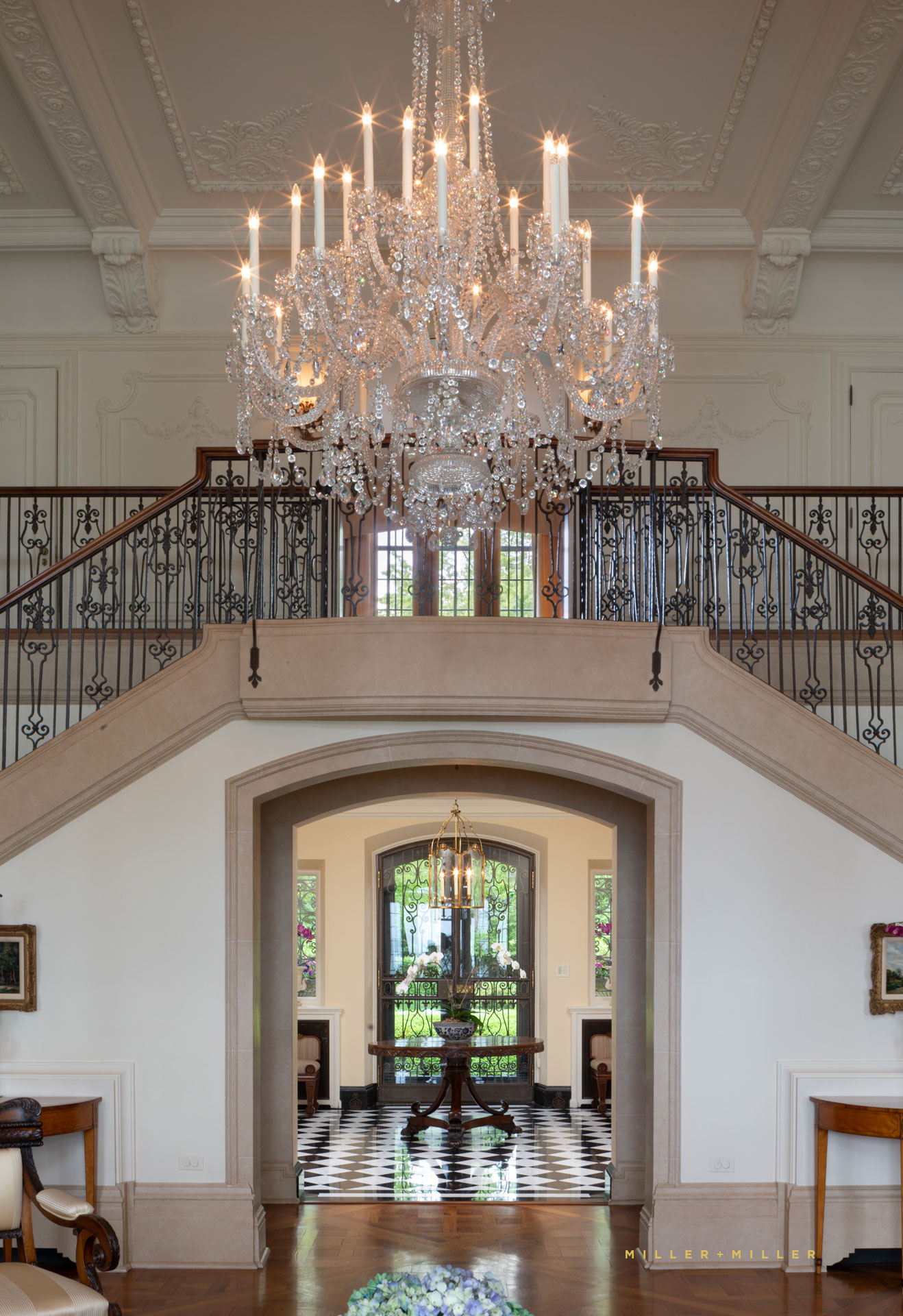 elegant french inspired entryway double wrought iron staircase with Venetian crystal chandelier baulsters juliette balcony